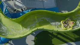 aerial-view-of-people-on-a-green-water-slide-in-a-circular-raft.webp